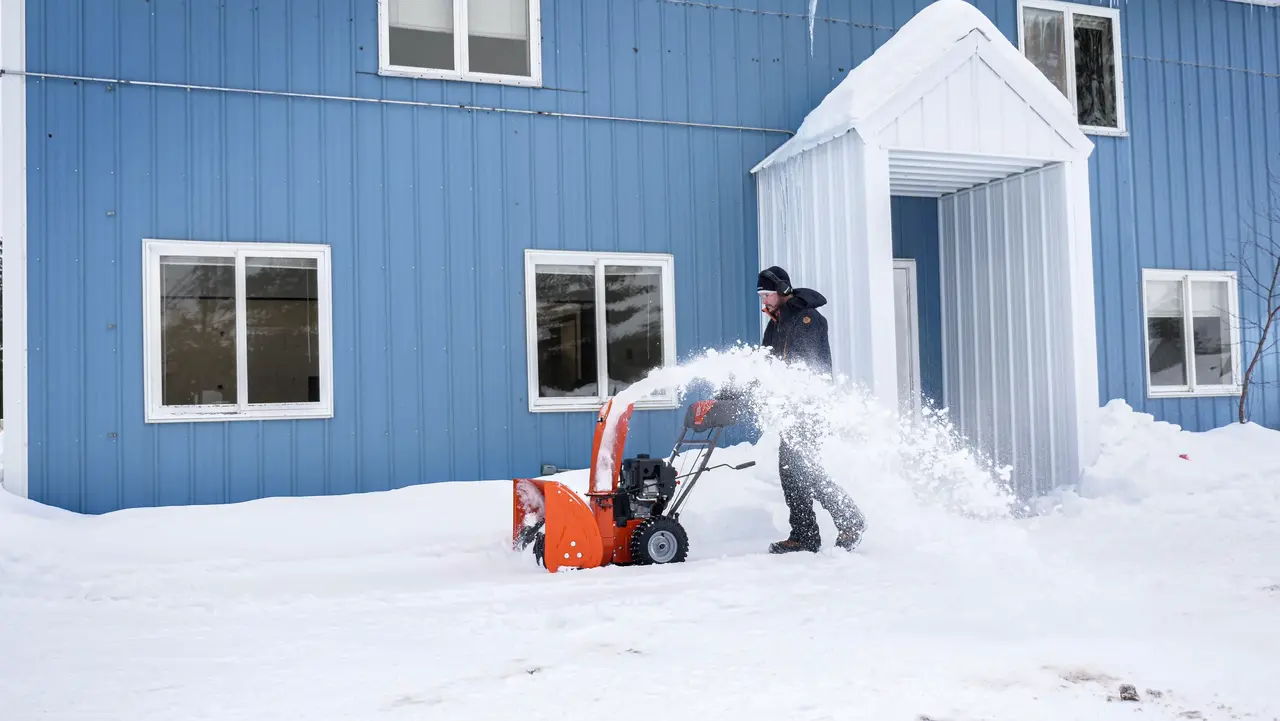 Snøfreser i arbeid forran blått hus